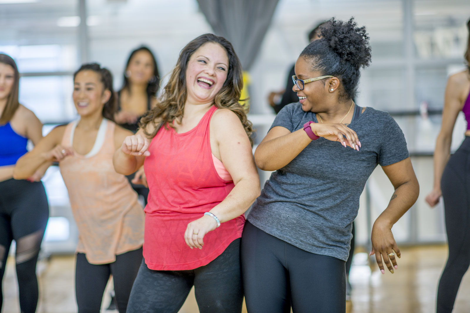 Frauen tanzen lachend in einem hellen Studio